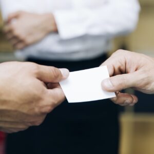 Close up of a business man handing someone a business card.