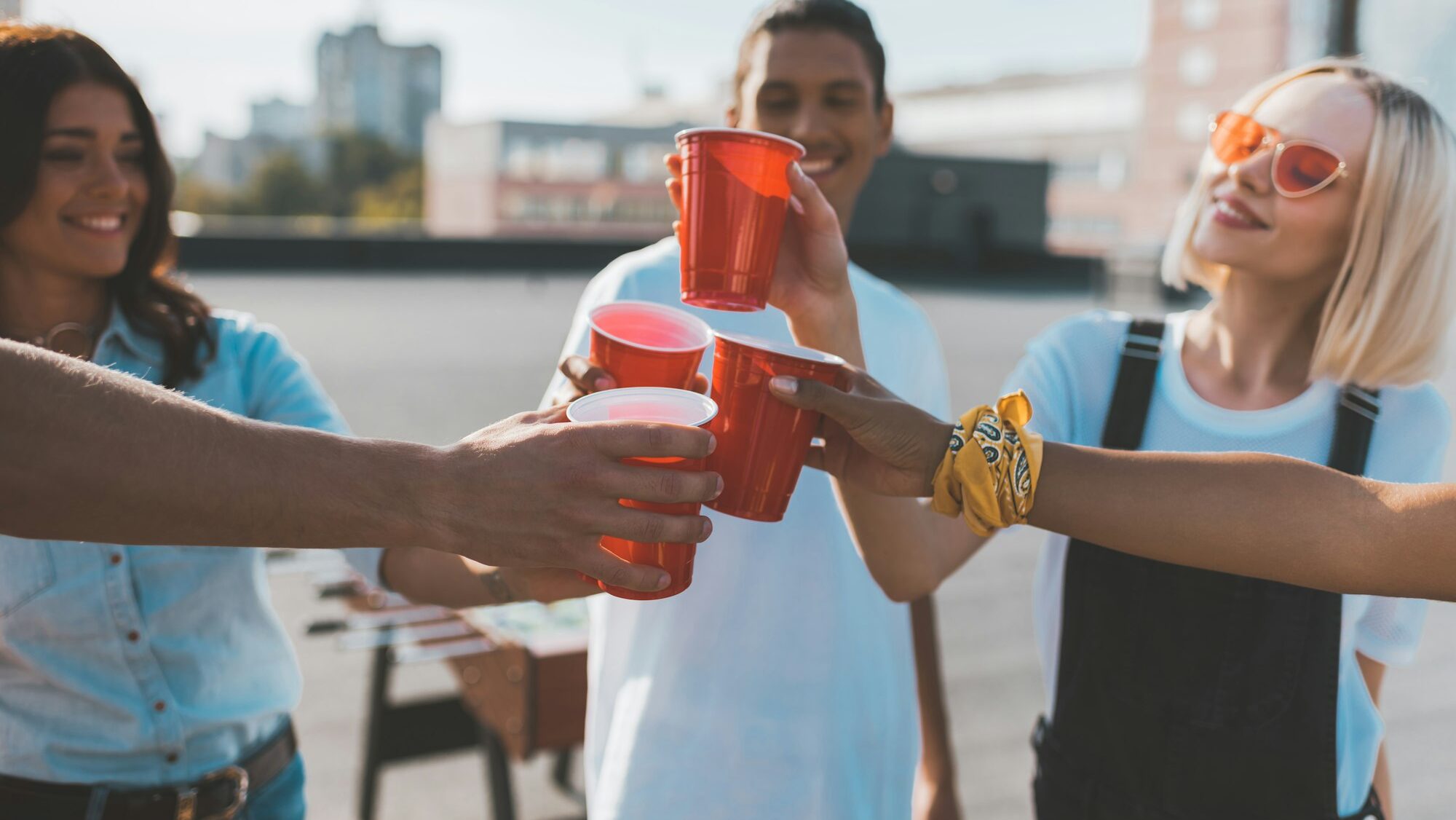 group of friends clinking glasses on alcohol on roof party